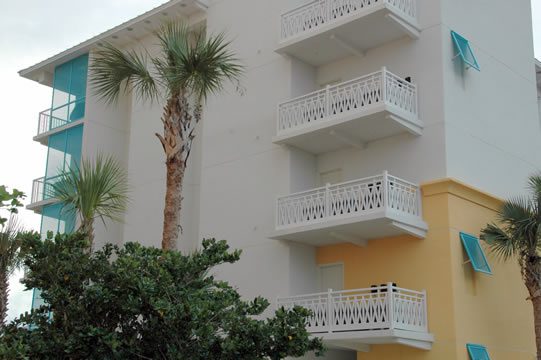 A building with balconies and architectural railings surrounded by palm trees.