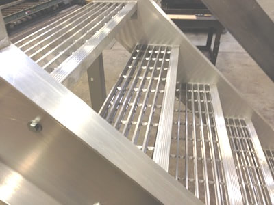 A closeup of an aluminum stair with focus on the grating on each step.